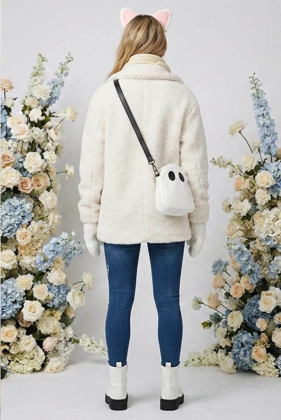 Front and rear views of a model wearing the FLY Clothing Co. "Plush Ears" winter outfit, featuring a white double-breasted sherpa coat, cream ribbed scarf, white cable-knit mittens, a white ghost-shaped crossbody bag, distressed blue skinny jeans, white combat boots with black lug soles, and a white plush ear headband with pink centers.