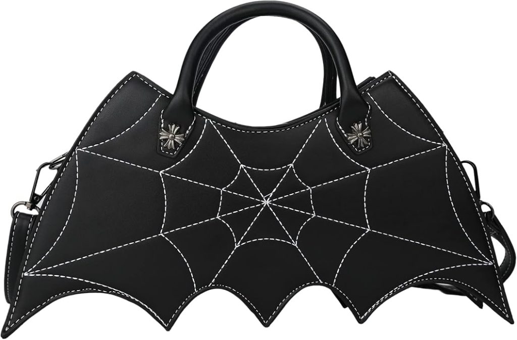 A studio product shot of the FLY Clothing Co. Bat Wing Shoulder Bag. The bag is made of sleek black vegan leather with a distinctive bat-wing silhouette on the sides. The front panel features an intricate white embroidered spiderweb design. It includes a silver-toned top zipper, a sturdy shoulder strap, and is shown hanging next to the "Spooky But Fly" hoodie to highlight the coordinated aesthetic.