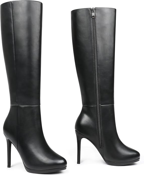 A pair of black, knee-high stiletto boots by FLY Clothing Co. The boots feature a sleek, polished vegan leather finish, a sharp pointed toe, and a high, thin stiletto heel. They are styled with a black leather mini skirt to create a seamless, leg-lengthening alternative streetwear look.
