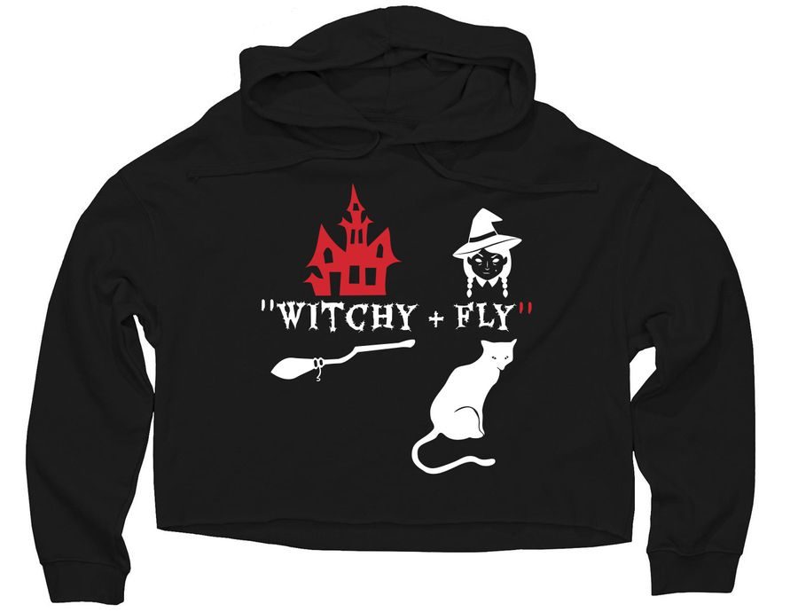 A front-facing product shot of a black cropped hoodie with "Witchy + Fly" printed in white text. The graphic features a red haunted castle, a white silhouette of a witch flying on a broomstick, a white cat, and a floating ghost.