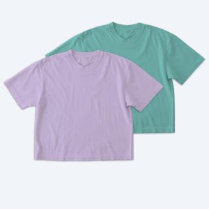 Two blank Comfort Colors boxy-fit unisex t-shirts, one in soft lavender and one in seafoam teal, displayed on a clean white background for custom apparel design services.