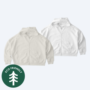Two eco-friendly custom Stanley Stella Women’s Stella Ida Zip Up Hoodies in cream and crisp white, featuring an "Eco-Friendly" seal, part of the Fly Clothing Co design service in LA and NYC.