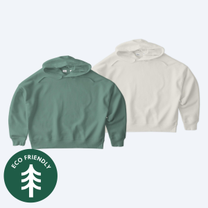 Two eco-friendly custom Stanley Stella Women’s Stella Nora Pullover Hoodies in sage green and off-white, featuring an "Eco-Friendly" seal, available through Fly Clothing Co’s design service in LA and NYC.