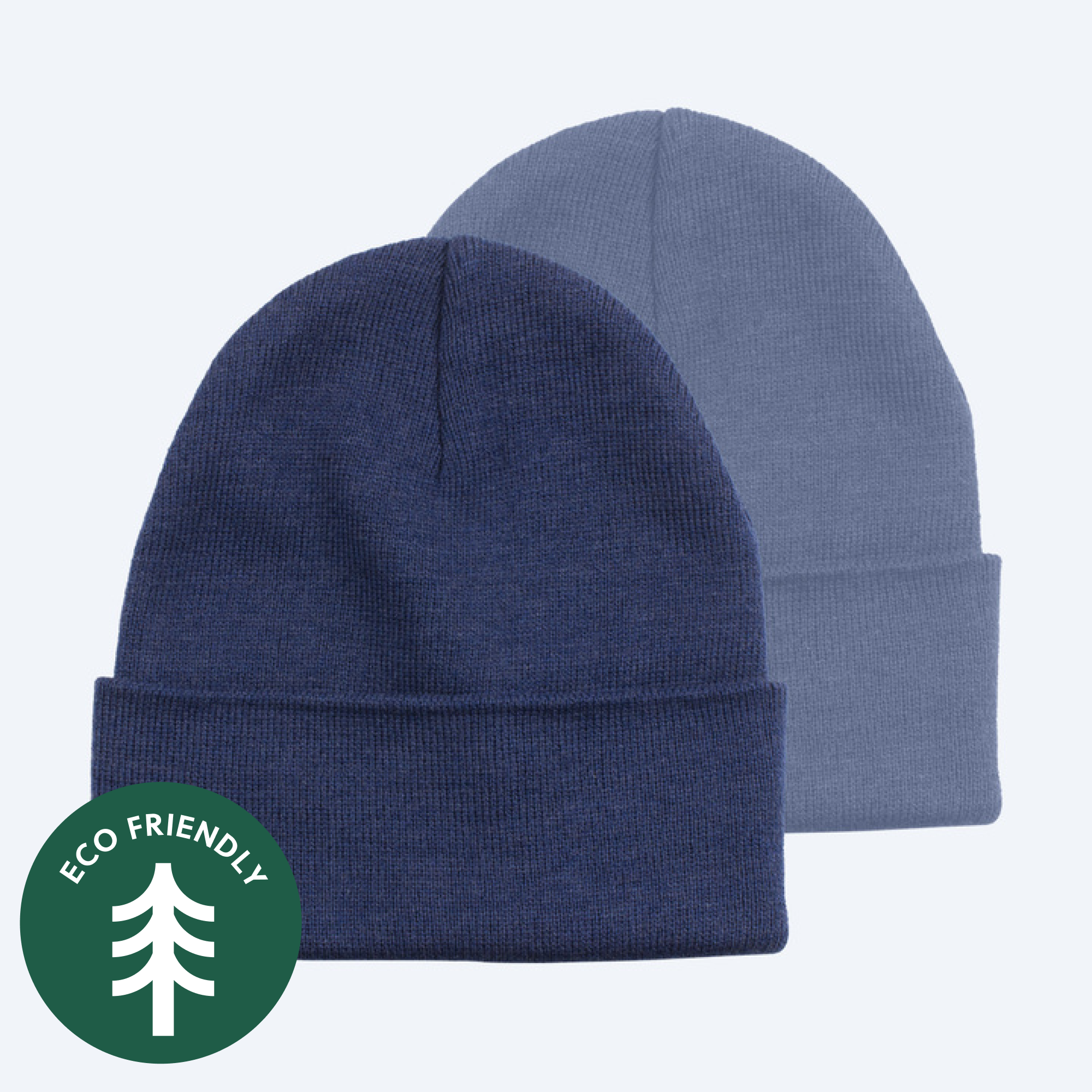 Two blank custom knit cuffed beanies, one in classic dark navy blue and one in a lighter denim blue, displayed on a clean white background with a green "Eco Friendly" tree icon for branding services.