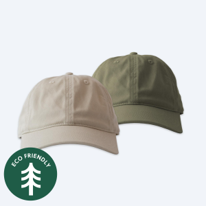 Two blank custom organic baseball caps, one in natural tan beige and one in classic olive green, featuring matching curved bills and displayed on a clean white background with a green "Eco Friendly" tree icon.