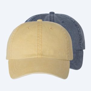 Two blank custom pigment dye baseball caps, one in washed mustard yellow and one in distressed navy blue, featuring curved bills and displayed on a clean white background for custom design services.