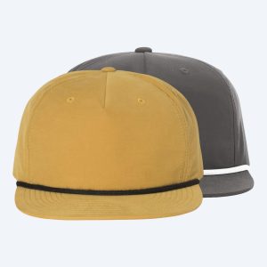 Two blank custom Umpqua snapback caps with flat bills and front rope detailing, one in mustard yellow with a black rope and one in charcoal grey with a white rope, displayed on a clean white background for custom printing design services.